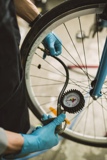 Mechaniker stellt den Reifendruck eines Fahrrads ein - RAEF000826