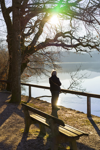 Deutschland, Bayern, Staffelsee, ältere Frau am Seeufer im Gegenlicht, lizenzfreies Stockfoto