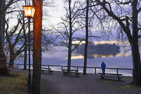 Deutschland, Bayern, Staffelsee, Seniorin am Seeufer in der Abenddämmerung - LAF001604