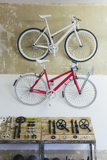 Zwei maßgefertigte Fahrräder hängen in einem Geschäft an der Wand - JUBF000095