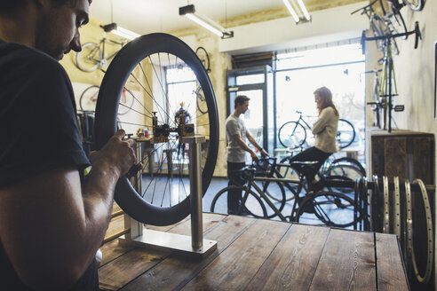 Mechanic, salesman and client in a custom-made bicycle store - JUBF000105