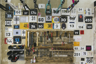 Zahlen und Werkzeuge hängen an der Wand in einer Werkstatt - JUBF000108