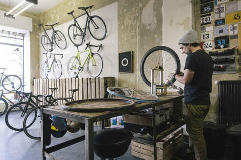 Mechanic working on tire in a custom-made bicycle store - JUBF000110