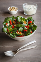 Schüssel mit gemischtem Salat, Seidentofu-Dressing, Gabel und Löffel auf Holz - EVGF002792