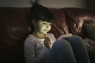 Portrait of little girl using games console at home - MGOF001331