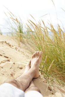 Schweden, Mellby, Mann liegt barfuß auf einer Stranddüne, Teilansicht - TSFF000002