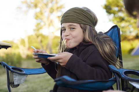 Mädchen isst Spaghetti auf einem Campingplatz, lizenzfreies Stockfoto