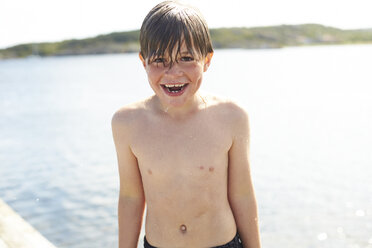 Sweden, Orust, laughing wet boy standing in front of the sea - TSFF000008