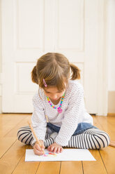 Kleines Mädchen sitzt auf Holzboden und malt mit Buntstiften - LVF004512