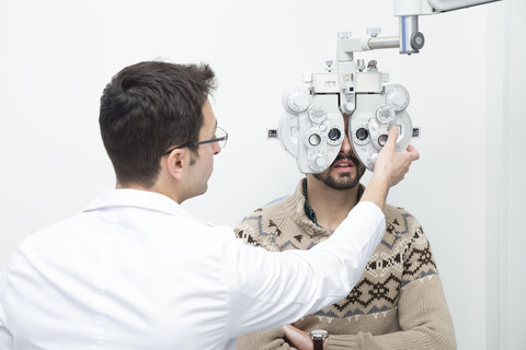 Optometrist untersucht die Sehkraft eines Mannes, lizenzfreies Stockfoto