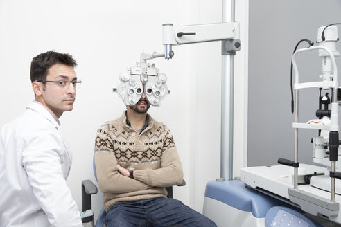 Optometrist untersucht die Sehkraft eines Mannes - ERLF000124