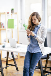 Junge Frau benutzt Smartphone im Büro - AKNF000040