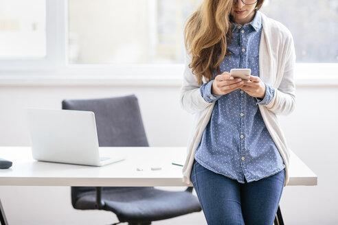 Young woman using smartphone in the office - AKNF000041