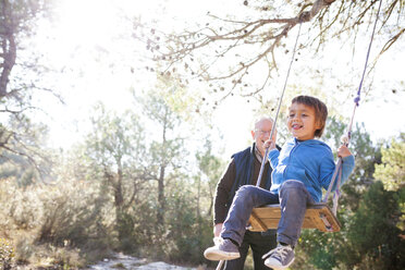 Spanien, Siurana, kleiner Junge hat Spaß auf einer Schaukel, während sein Großvater ihn beobachtet - VABF000135