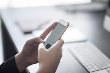 Nahaufnahme einer Frau, die ein Mobiltelefon im Büro hält - ZEF008332