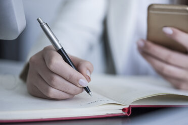 Close-up of woman at desk taking notes - ZEF008335