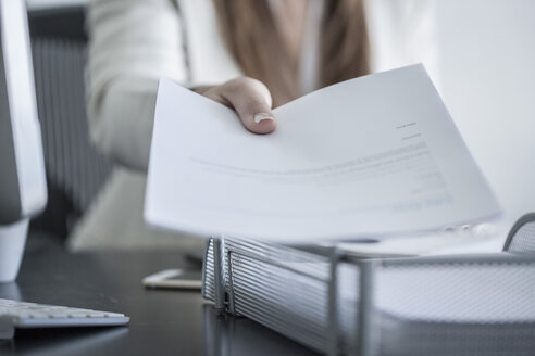 Close-up of woman at desk handing over a document - ZEF008340