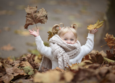Happy blond girl with big scarf throwing autumn leaves in the air - NIF000068