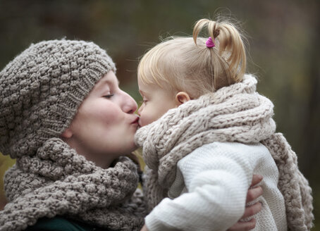 Young woman kissing her little daughter in autumn - NIF000070
