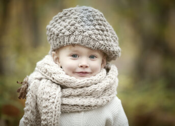 Porträt eines glücklichen kleinen Mädchens mit großem Schal und Wollmütze im Herbst - NIF000072