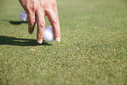 Nahaufnahme der Hand eines Mannes, der einen Golfball nimmt - ABZF000188