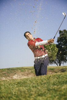 Golfer, der einen Golfball aus einem Sandbunker auf einem Golfplatz schlägt - ABZF000190