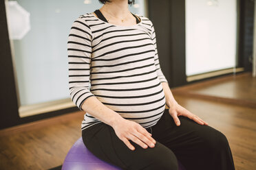 Schwangere Frau macht Pilates-Übungen mit Gymnastikball in einem Fitnessstudio - RAEF000837