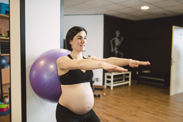 Pregnant woman doing Pilates exercises with gymnastics ball in a gym - RAEF000846