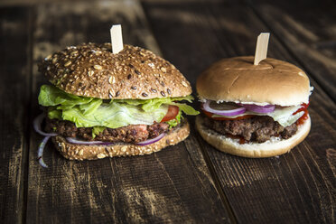 Vegetarischer Burger mit Rote-Bete-Patty, Avocadocreme, Salat und Zwiebeln neben einem Hamburger mit Frikadelle rechts - SARF002536