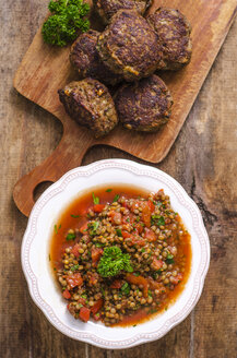 Linsen-Tomaten-Salat mit Petersilie in der Schüssel und hausgemachte Patties auf dem Schneidebrett - ODF001371