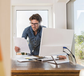 Junger Mann arbeitet im Büro zu Hause - UUF006503