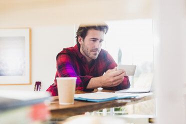 Porträt eines jungen Mannes, der auf sein Smartphone schaut - UUF006511