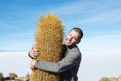 Bolivia, Atacama, Altiplano, Salar de Uyuni, man embracing cactus - GEMF000703