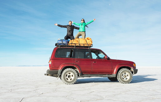 Bolivien, Salar de Uyuni, Pärchen kniend auf einem 4x4 Auto - GEMF000713
