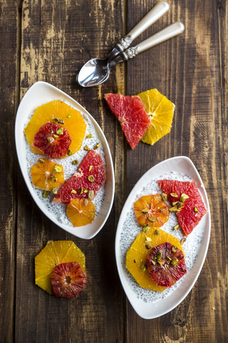 Chia Pudding und Orangenscheiben Blutorange und Grapefruit, Schalen auf Holz, lizenzfreies Stockfoto