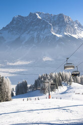 Austria, Tyrol, Lermoos, chair lift in winter landscape with view to Zugspitze - AMF004749
