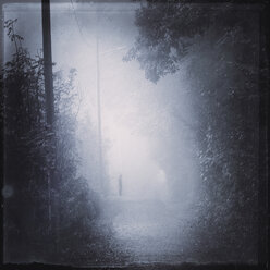 Silhouette of a man on path during fog - DWIF000688