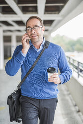 Businessman with cell phone and coffee to go on the move - UUF006534