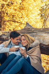 Lächelndes Paar mit Tassen im Herbstwald - CHAF001592