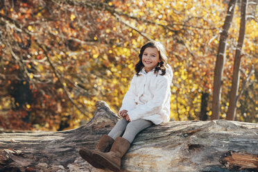 Porträt des glücklichen Kleinen, der auf totem Holz im Wald sitzt - CHAF001638
