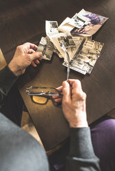 Die Hände einer älteren Frau halten eine alte Fotografie und eine Brille - DEGF000608