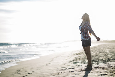 Spain, Tarragona, young woman standing at seafront with arms outstretched - JRFF000392