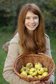 Porträt eines lächelnden Mädchens, das einen Weidenkorb mit Quitten hält - LBF001367