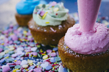 Icing bag decorating a cupcake with pink cream, close-up - ABZF000191