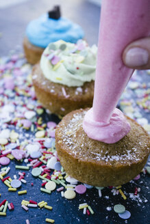 Spritzbeutel, der einen Cupcake mit rosa Sahne verziert, Nahaufnahme - ABZF000192