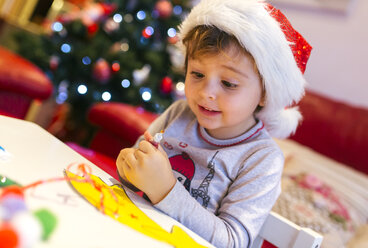 Porträt eines kleinen Mädchens, das Weihnachtsdekoration bastelt - MGOF001352