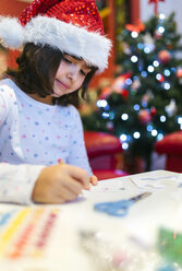 Porträt eines kleinen Mädchens mit Weihnachtsmütze, das Weihnachtsschmuck bastelt - MGOF001358