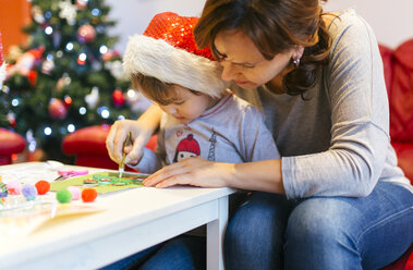 Mutter hilft ihrer kleinen Tochter beim Basteln von Weihnachtsdekoration - MGOF001359