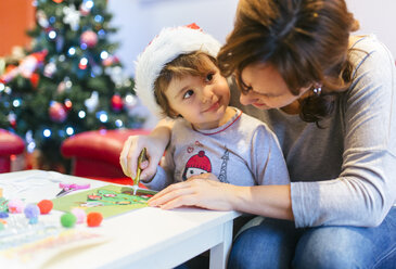Mutter hilft ihrer kleinen Tochter beim Basteln von Weihnachtsdekoration - MGOF001360