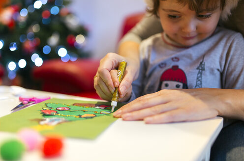 Mutter hilft ihrer kleinen Tochter beim Basteln von Weihnachtsdekoration - MGOF001361